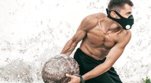Muscular man doing medicine ball workout wearing a training mask