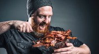 Hungry bearded man eating a bucket of bacon on the keto diet