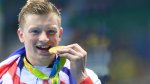 Olympic gold medal swimmer Adam Peaty biting his gold medal