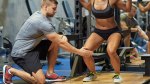 Male personal trainer training a fit female to properly do a barbell squat and squat swap outs