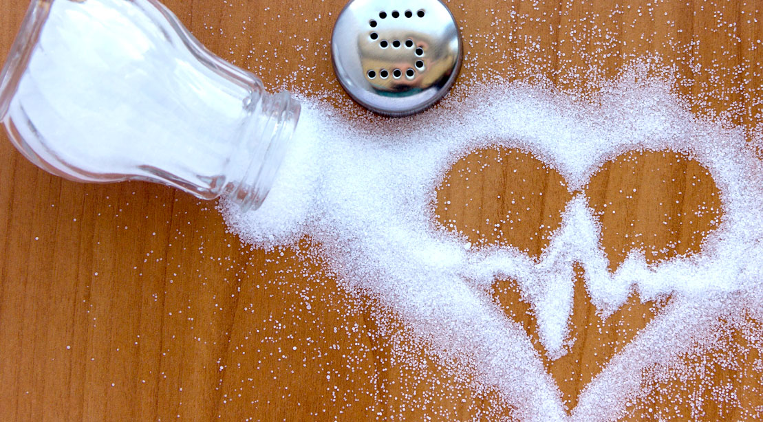Spilt salt on wooden table in the shape of a heart and heart beat