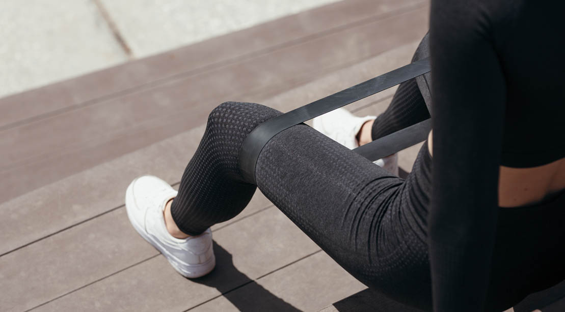 Female working out with a resistance band doing a seated clam shell exercise