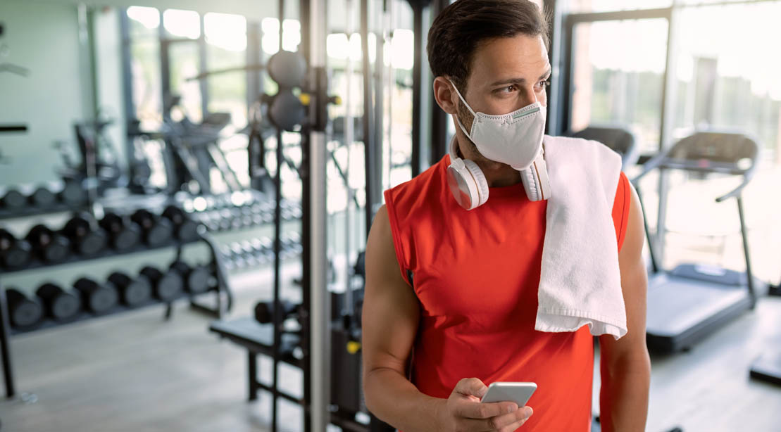 Physically fit gym goer wearing a mask in a gym