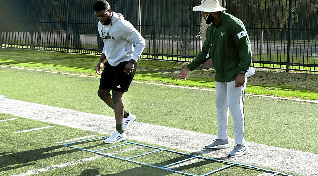 University of South Florida’s Director of Football Strength and Conditioning AJ Artis Showing An Athlete His Footwork Ladder Drill for Agility