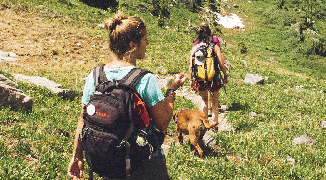 Two female hikers hiking on a hiking trail carrying hiking gear
