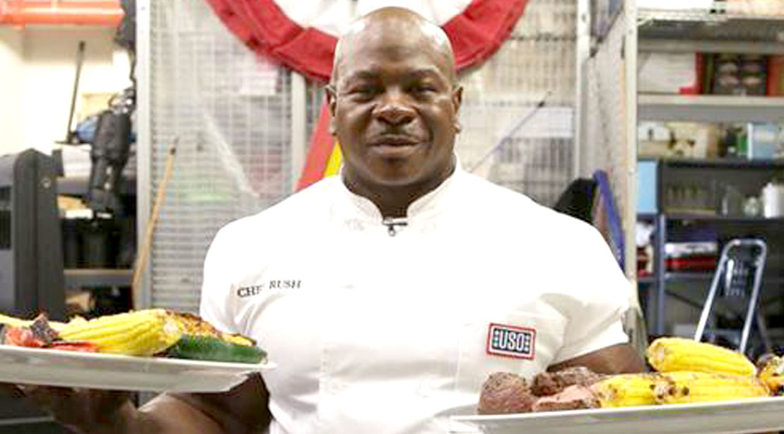 Celebrity chef Andre Chef Rush serving two plates of healthy food to the USO