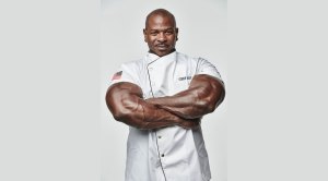 Chef Andre Rush with his massive arms crossed wearing a chef jacket
