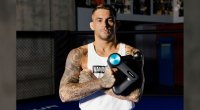 UFC and MMA fighter Dustin Poirier holding a massage gun from Therabody