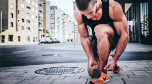 Muscular runner tying his running shoes for a leg workout for runners