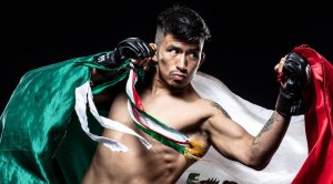 MMA Fighter Leo Muniz throwing a left uppercut while holding the Mexican flag