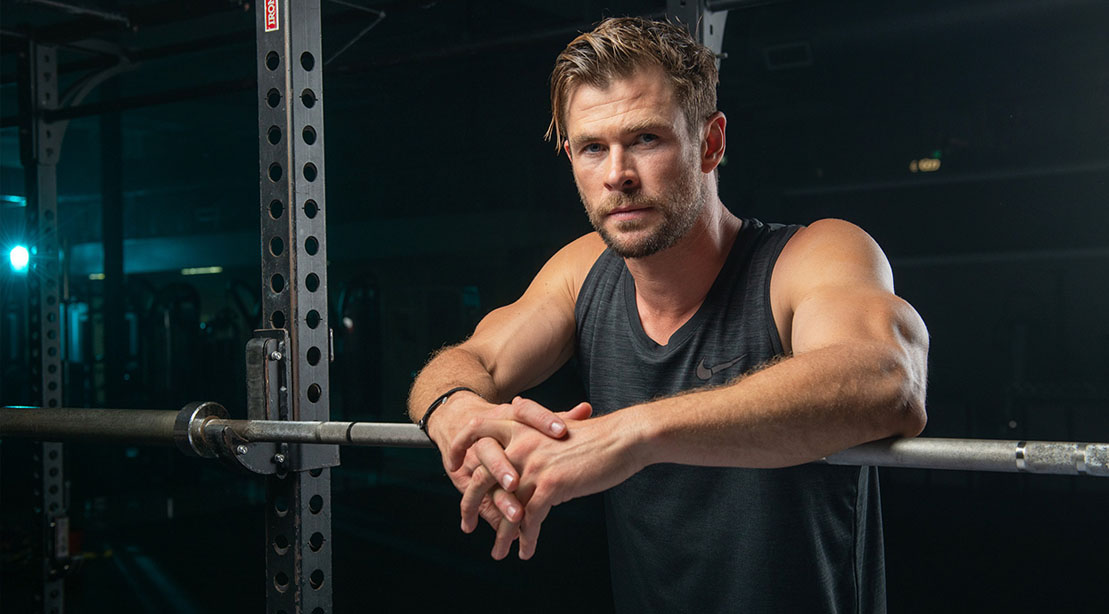 Actor Chris Hemsworth resting on a barbell bar after his 10 minute bodyweight circuit workout