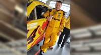 Nascar driver Michael McDowell drinking a can of Celsius next to his race car