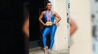 IIFBB female bodybuilder Viktoria Grygorian wears a spandex singlet with her Olympic medals on it