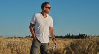 NFL Hall of Famer for the Dallas Cowboys Troy Aikman drinking a beer in a wheat field