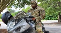 Bodybuilder Cedric McMillan in his army uniform on a motorcycle