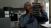 Actor Titus Welliver looking at film negatives as Detective Bosch in Bosch-Legacy