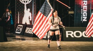 Gabriele Burgholzer walking on a strongwoman competition stage holding the American Flag