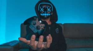 Gamer holding a levitating X Box controller in a LED lit room while practicing exercises for gamers