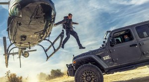 Bear Grylls host of Disney's The Challenge jumping onto a moving jeep from a airborne helicopter