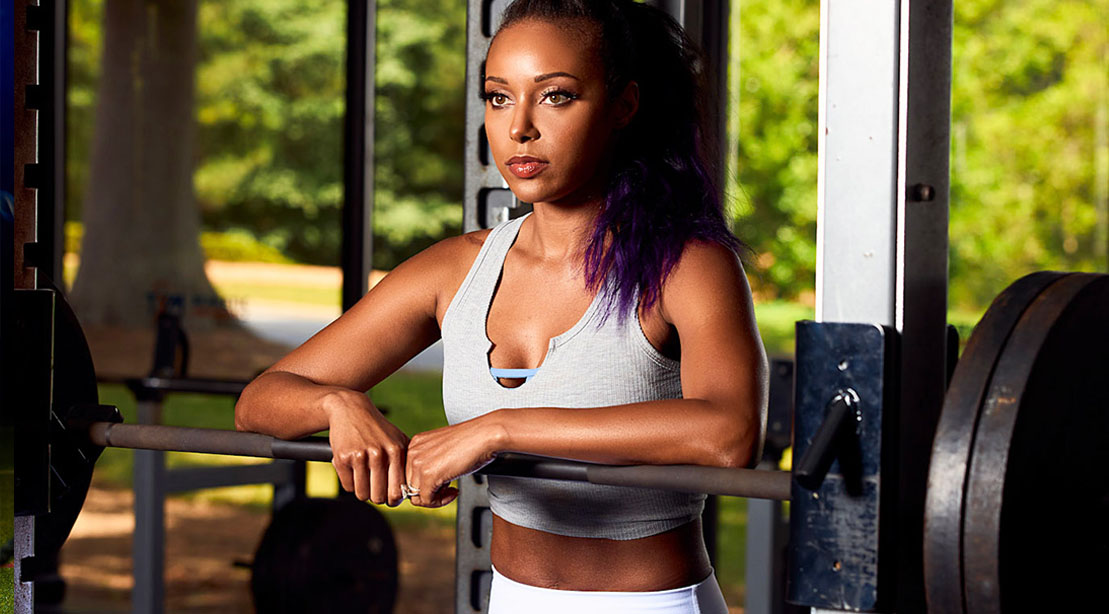 Female wrestler and wife to Cody Rhodes Brandi Rhodes standing behind a barbell bench