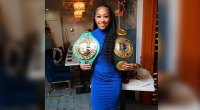 Female boxer Alycia Baumgardner wearing a blue maxi dress and holding her championship boxing belts