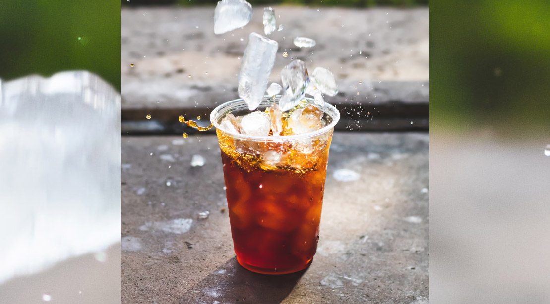 Ice falling into a cup of cold brew coffee