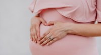 Pregnant woman with her hands in the shape of a heart over her pregnant belly