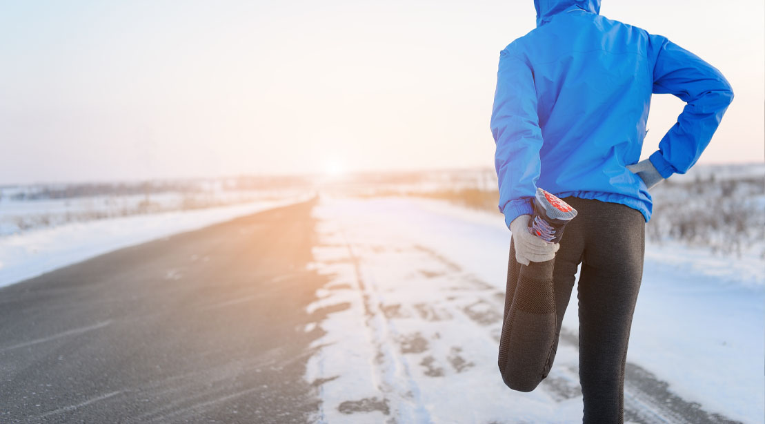 Female stretching her legs in the snow before performing her cold weather training routine
