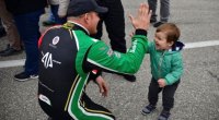 Caesar Bacarella high-fives a toddler while wearing his Alpha Prime race suit