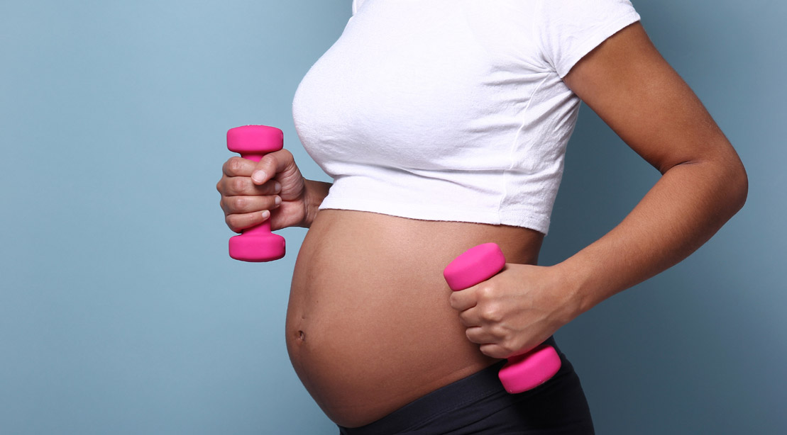 Pregnant woman lifting pink dumbbells