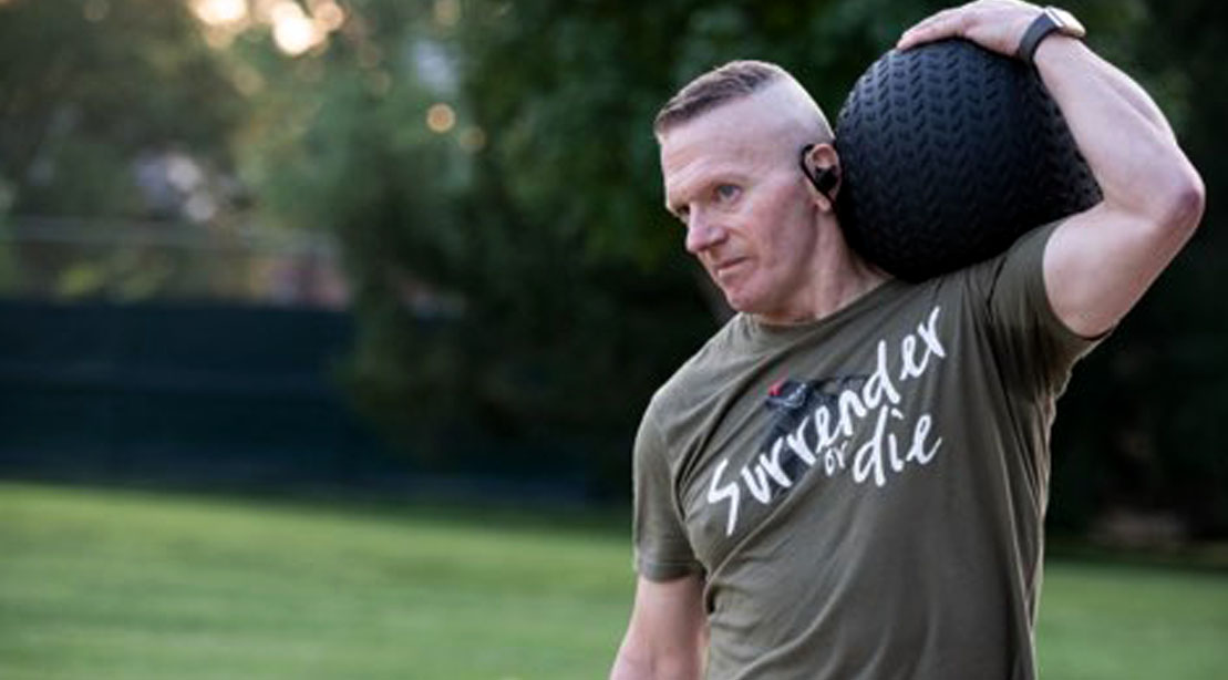 SEAC John Troxell realizando um exercício ao ar livre com uma bola medicinal
