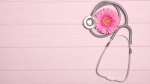 Stethoscope next to a pink flower on a pink picnic table