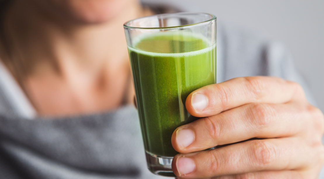 Fit female holding a drink full of greens powder