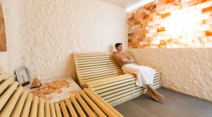 Man sitting in a dry sauna surrounded by salt blocks