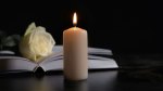 White candle and white rose on a book