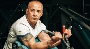 Older fit man performing working out at a bicep curl machine