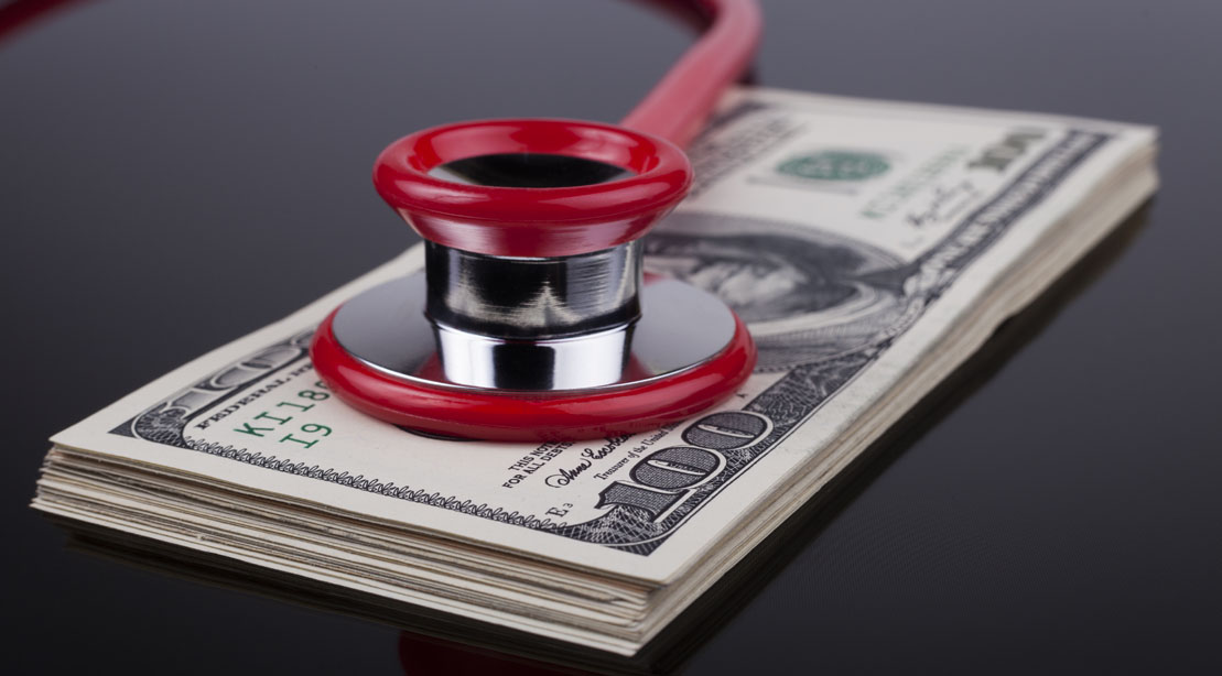 Red stethoscope on top of a stack of money
