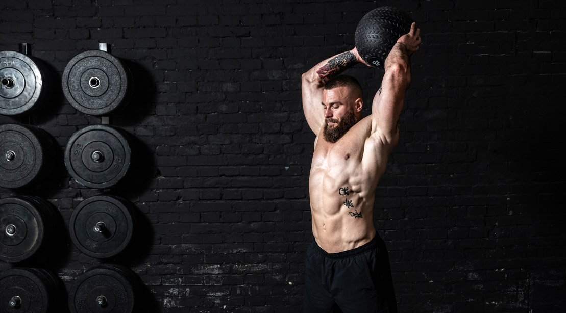 Muscular man performing power training exercises to build power with a medball slam