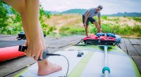 Beginner stand up paddleboarding straps the paddleboard to her ankle