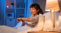 Frau schaut vor dem Schlafengehen auf ihre Smartwatch