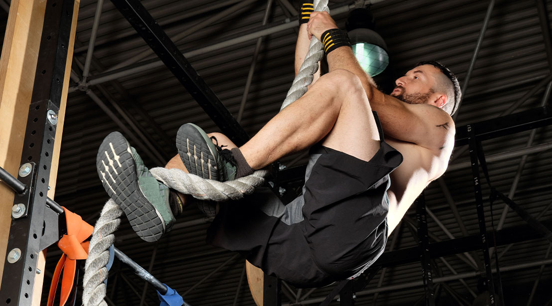 Muscular man using the J-Hook rope climbing technique
