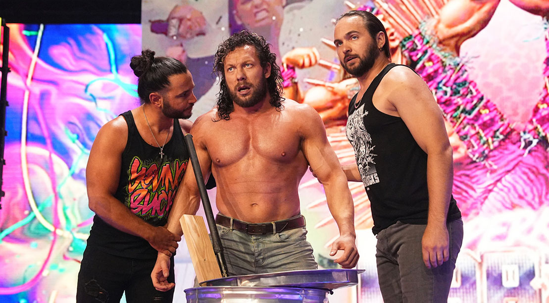 Wrestler Kenny Omega surrounded by his fellow wrestlers