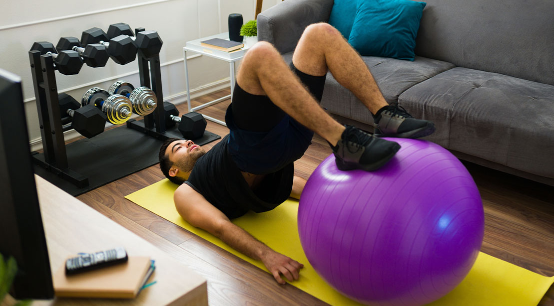 Man performing a Stability Ball Hip Extension Hamstring Curl Exercise