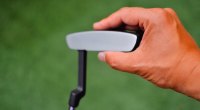 Man touches the head of a putter