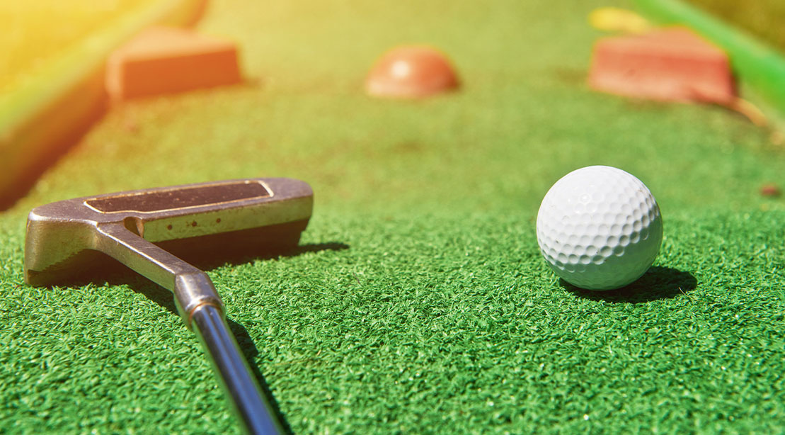 Putter next to a golf ball on a putting course