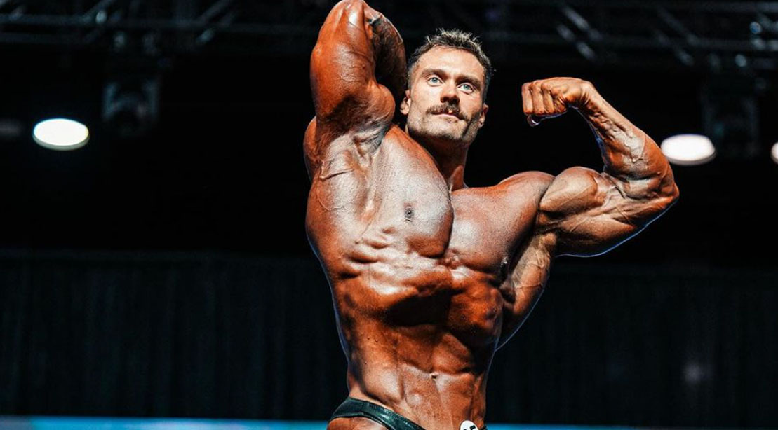 Bodybuilder and 2023 Classic Physique Winner Chris Bumstead posing on stage at the 2023 Olympia Competition