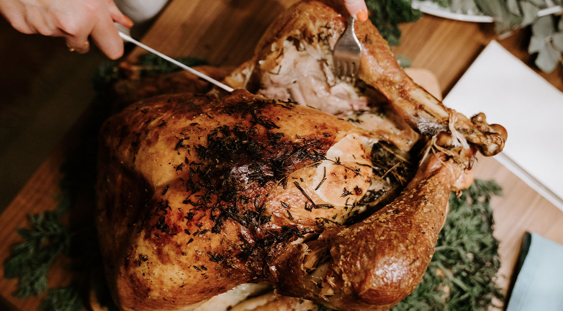 Person carving an air fryer turkey on a cutting board for thanksgiving