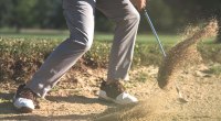 Golfer in the sand bunker using his sand wedge to get out